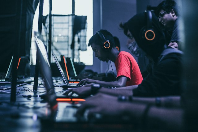 Gamers with headsets playing on Laptops